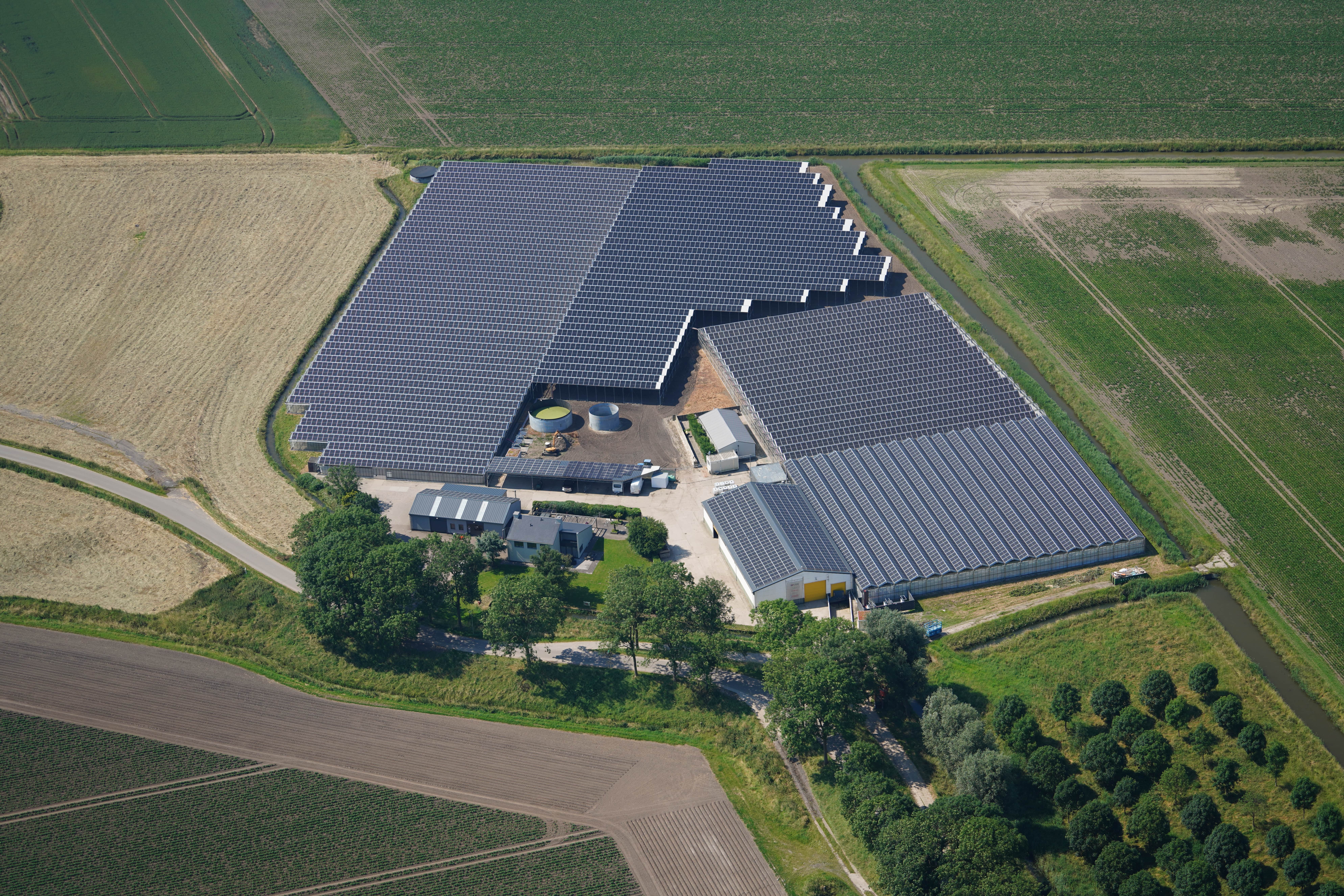 Overzicht van meerdere kassen met geïntegreerde zonnepanelen op één terrein, gerealiseerd door ETURN